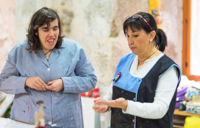 People with a disability working with their teachers at workshop