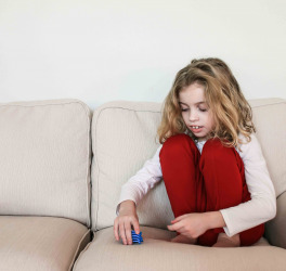 a child with autism sitting alone on a couch, stacking toys instead of playing with them in the usual manner