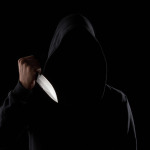 A dangerous hooded man standing in the dark and holding a shiny knife