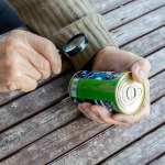 man reads composition of food product with magnifier. Fine print on can.