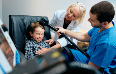 Paediatrician Doctor Doing Brain Treatment To Autistic Child In Clinic