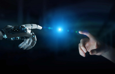 Robot hand making contact with human hand on dark background