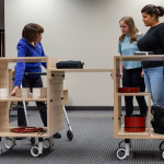 RIT students Andrea Gonzalez, far right, and Emma Canning, center, demonstrate the capabilities of MO:KI, a mobile kitchen
