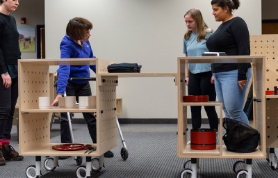 RIT students Andrea Gonzalez, far right, and Emma Canning, center, demonstrate the capabilities of MO:KI, a mobile kitchen