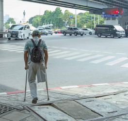 Male with a disability without a leg on crutches waiting to across the road.