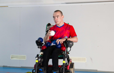 A disabled man in a wheelchair. Holding a white little ball.