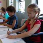 Schoolgirl sitting in a wheelchair in an elementary school classroom.