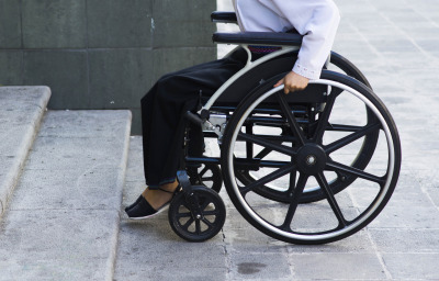 woman in wheelchair in front of inaccessible building