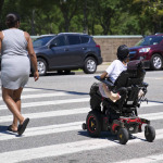 a woman in electonic wheelchair crossing street