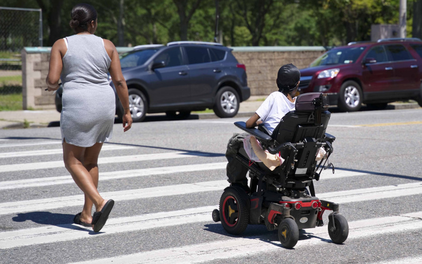 a woman in electonic wheelchair crossing street