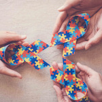 Hands holding puzzle ribbon for autism awareness
