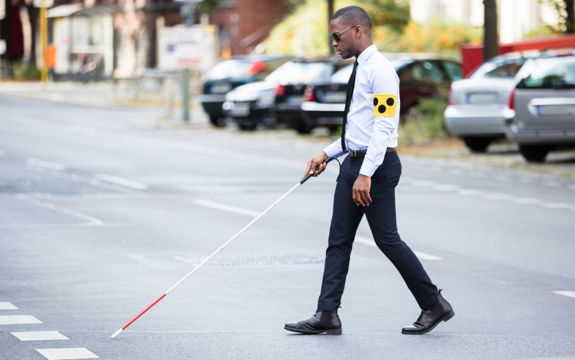 Young African Blind Man Wearing Armband Walking With Stick Crossing Road