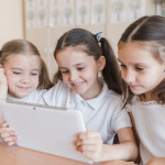 Cheerful girl using tablet in classroom