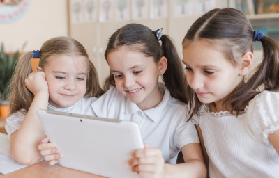 Cheerful girl using tablet in classroom