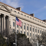 Exterior of Washington D.C, Justice department building with American flag in foreground, U.S.A.