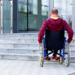 man in wheelchair in front of stairs