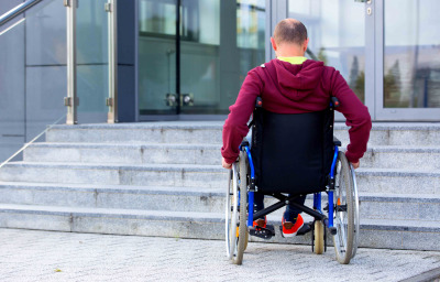man in wheelchair in front of stairs