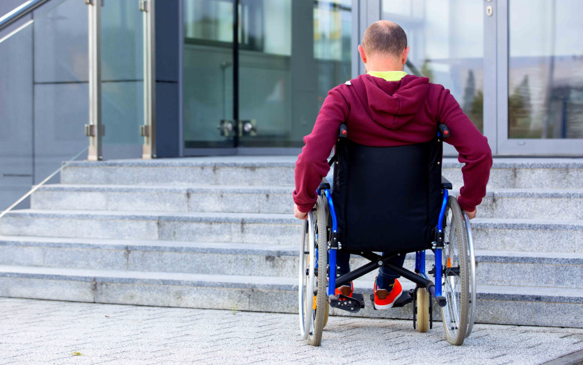 man in wheelchair in front of stairs
