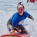 Surfer girl with disability having a blast on the waves at Beach