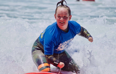 Surfer girl with disability having a blast on the waves at Beach