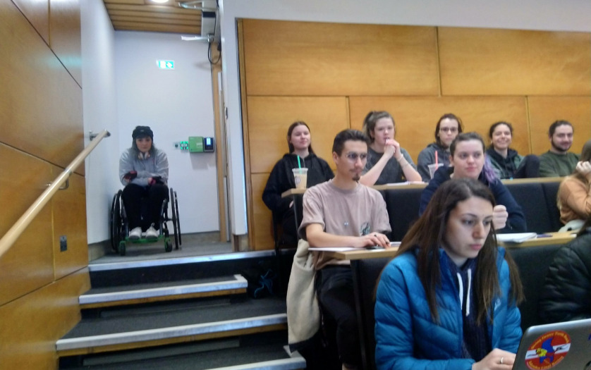 A wheelchair user at the top of steps in a lecture theatre