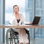 Young business woman in wheelchair working in office