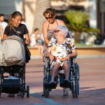 A woman pushing the wheelchair with his mother over.