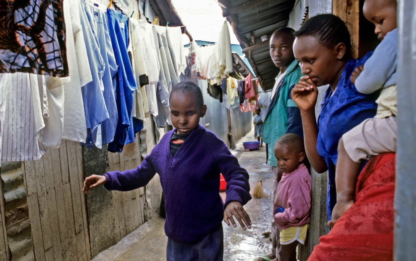 a blind boy to walk alone in a narrow corridor between the shacks, hovels, houses of corrugated iron or wood, slum, Nairobi