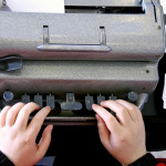 Flat lay view of hands of a person typing on a braille typing machine