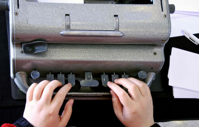 Flat lay view of hands of a person typing on a braille typing machine