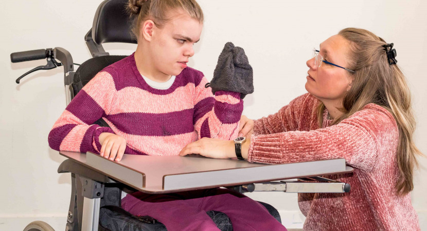 A disabled child in a wheelchair being cared for by a voluntary care worker who is helping with personal hygiene.