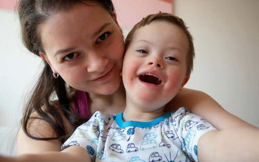 Selfie of cute small boy with Down syndrome with his young mother