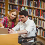 Student in wheelchair working with a classmate in library