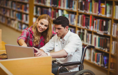 Student in wheelchair working with a classmate in library