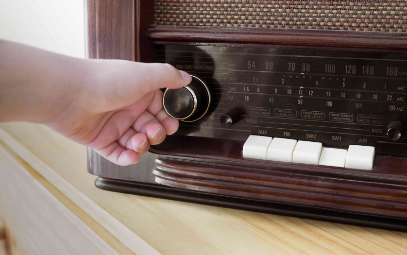 A woman hand adjusting the button vintage radio volume for listen news