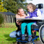 Child in a wheelchair relaxing outside with a care assistant