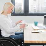 Side view of woman in wheelchair working at desk