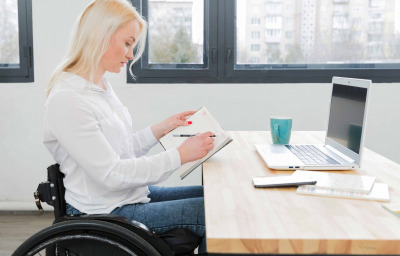 Side view of woman in wheelchair working at desk