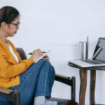 young asian woman taking notes while participating in the webinar at home