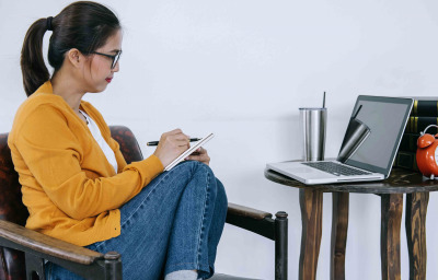 young asian woman taking notes while participating in the webinar at home