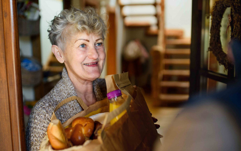courier delivering shopping to senior woman