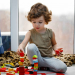 Little autistic boy playing with cubes at home