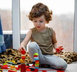 Little autistic boy playing with cubes at home