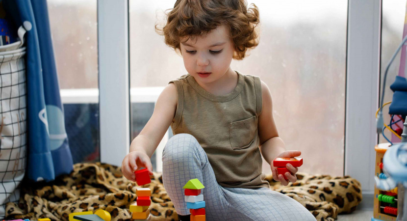 Little autistic boy playing with cubes at home