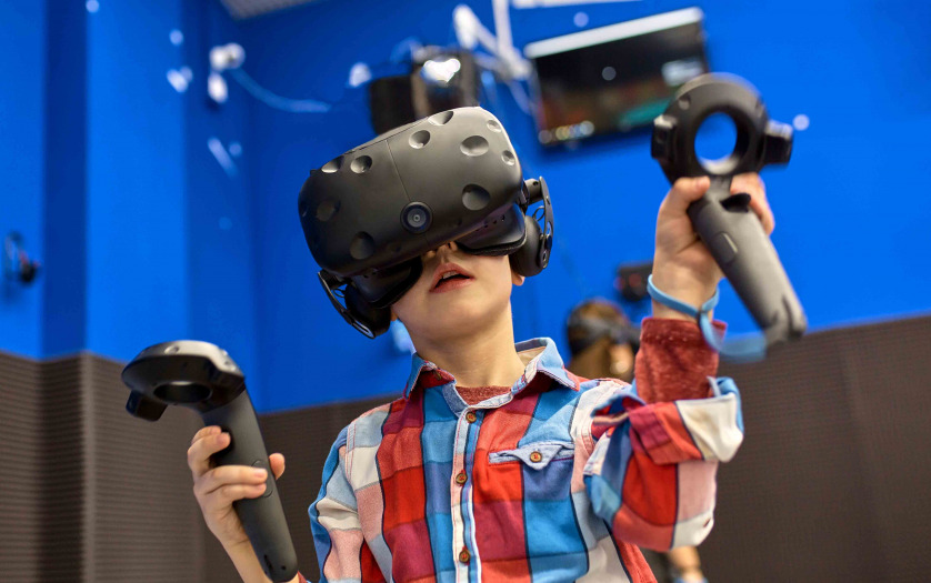 boy in virtual reality headset playing videogame