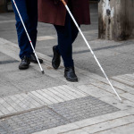 Blind man and woman walking on the street using a white walking stick