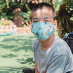 child in wheelchair wearing a protection mask