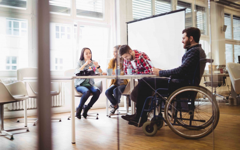Coworker on wheelchair with photo editors in meeting room