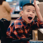 kid in wheelchair waiting for a meal at the table