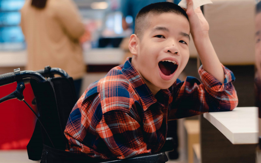 kid in wheelchair waiting for a meal at the table